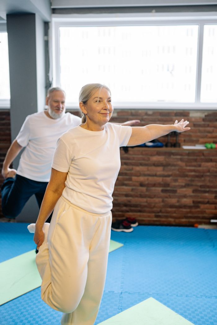 Senior adults engaging in yoga exercise indoors, promoting healthy lifestyle and fitness.